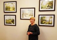 L.Ašmonaitienė - prie savo tapytų peizažų.